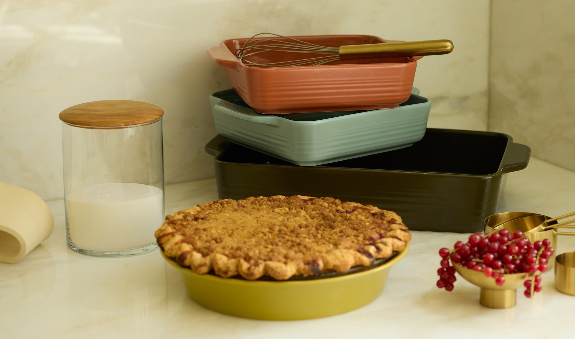 Warmly coloured bakeware and kitchen essentials on a stone counter